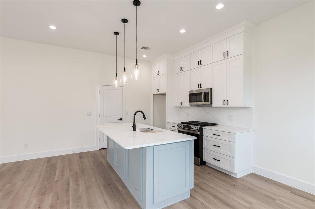The kitchen features floor-to-ceiling cabinetry, stunning quartz countertops with a matching backsplash, and a gas range—truly a chef’s dream come to life.