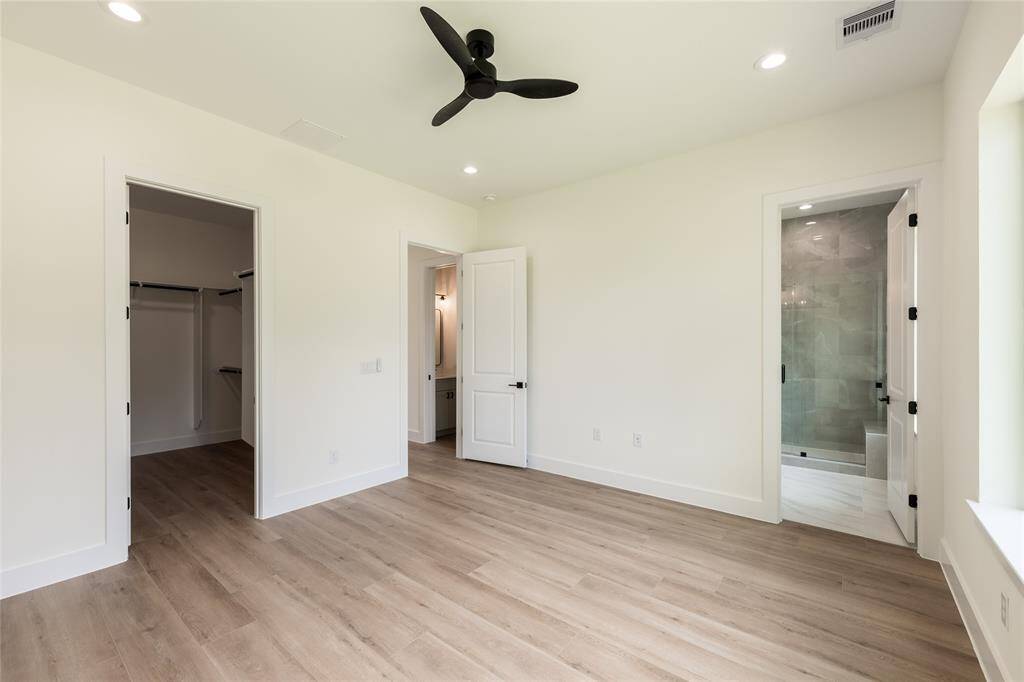 Another view of the sunlit primary bedroom, offering a glimpse of the generous walk-in closet—perfect for organized and stylish living.