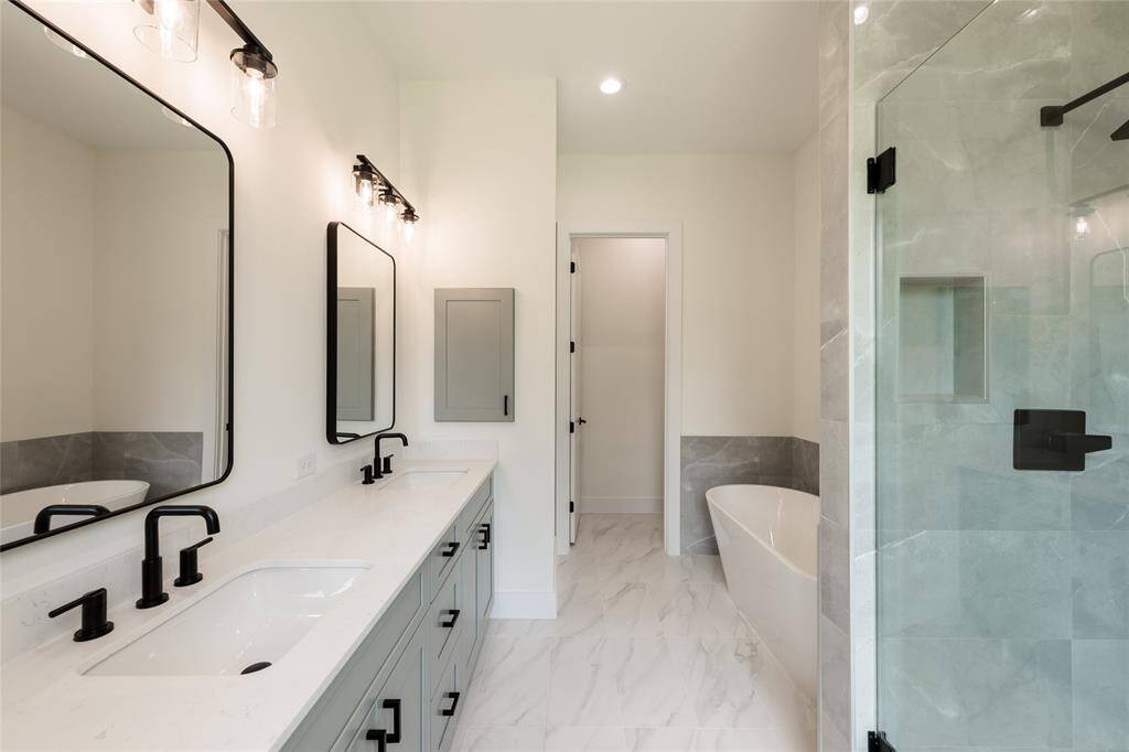 Luxurious primary bathroom featuring a freestanding soaking tub, a sleek standing shower with a built-in seat and niche for tidy storage, adorned with elegant luxury tiles, plus double sinks—combining style and functionality in a serene, spa-like retreat