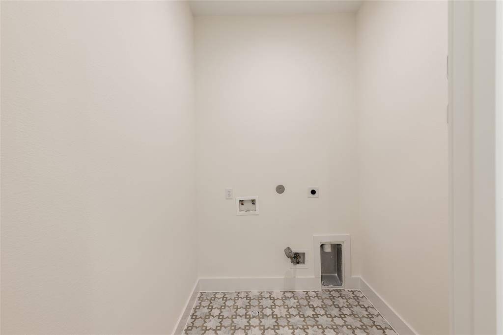 Spacious upstairs utility room featuring elegant tile flooring perfectly located next to the primary bedroom for added convenience.