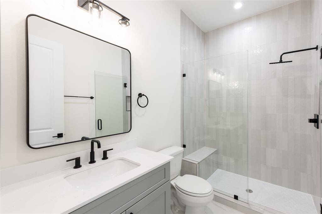 Full bathroom on the first floor, located conveniently between the bedrooms, featuring a standing shower with built-in seat and recessed niche for organized storage.