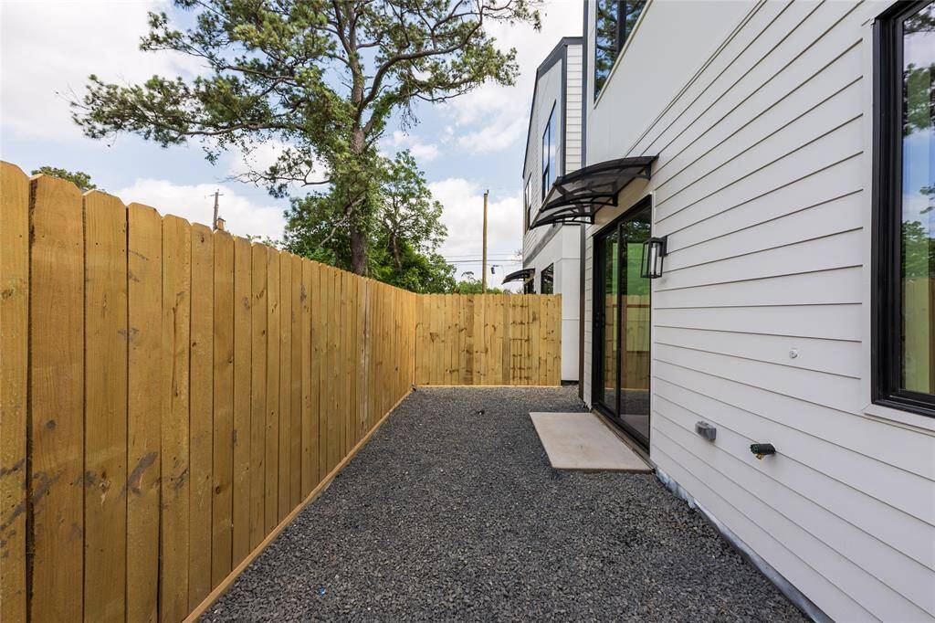 Backyard with a covered awning providing ample shade, complemented by low-maintenance gravel landscaping for easy care and lasting beauty.