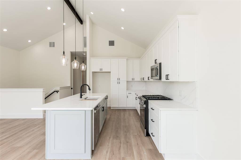 Alternate view of the chef’s dream kitchen showcasing the expansive island with sink, abundant cabinetry, and warm under-cabinet lighting—perfectly designed for cooking and entertaining.