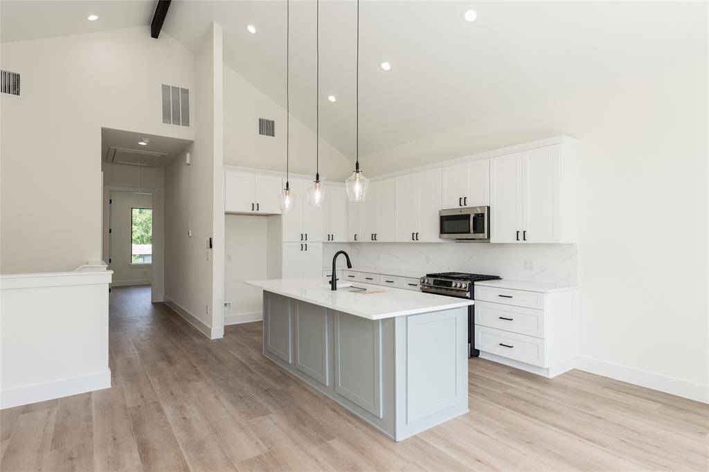 Alternate view of the chef’s dream kitchen showcasing the expansive island with sink, abundant cabinetry, and warm under-cabinet lighting—perfectly designed for cooking and entertaining.
