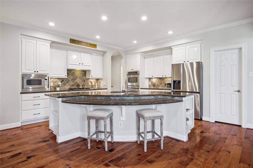 The open island kitchen impresses with granite countertops, stainless appliances, and underlit cabinetry. The archway in the center connects the kitchen to the formal dining room so you can entertain with ease.