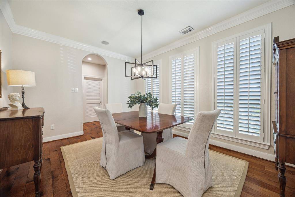 Through the archway just next to the study is the formal dining room. Tall windows with plantation shutters, thick crown molding and a center chandelier create an elegant dining space.