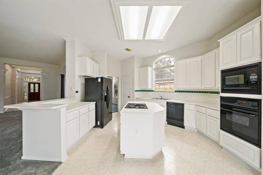 This bright kitchen offers a generous layout with a breakfast bar, abundant white cabinetry, and sleek countertops — perfect for both cooking and entertaining.