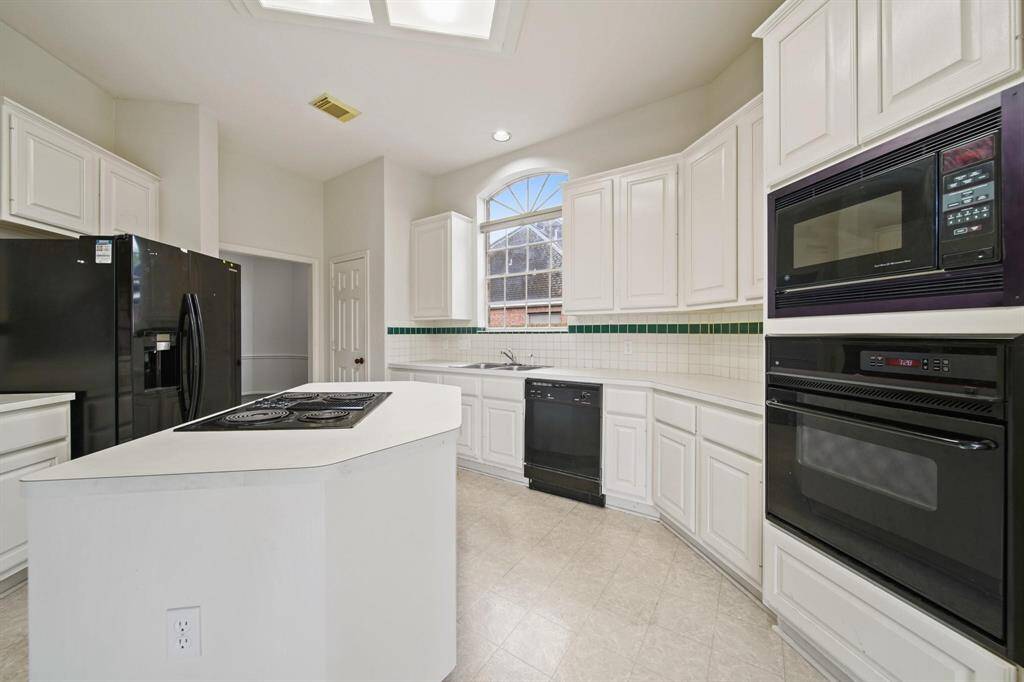 Equipped with stainless steel appliances, including a built-in microwave, double oven, and dishwasher, this kitchen combines functionality with modern style.