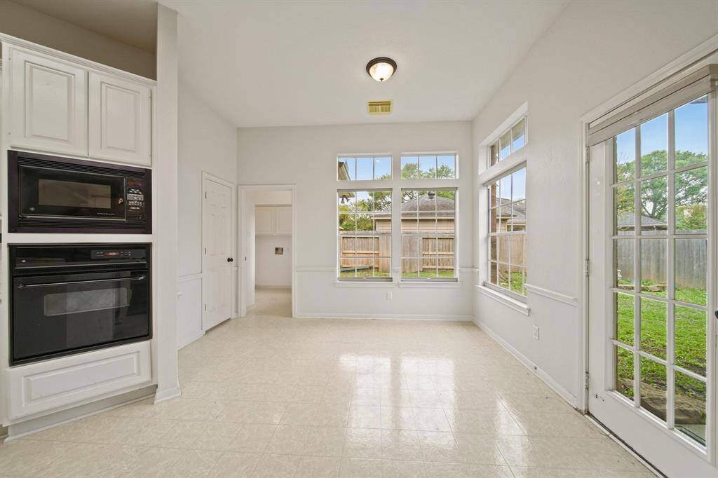 Large French-style windows flood the space with natural light, creating an inviting atmosphere while providing a view of the lush backyard.