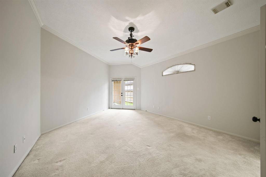 This primary bedroom boasts a high ceiling, complemented by plush carpet flooring and a walk-in access outside that provides the perfect retreat after a long day.