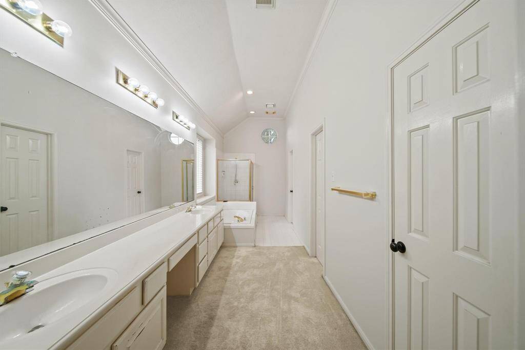 This generously sized primary ensuite bathroom features a dual-sink and vanity with plenty of storage beneath the sinks keeps the space both functional and organized.