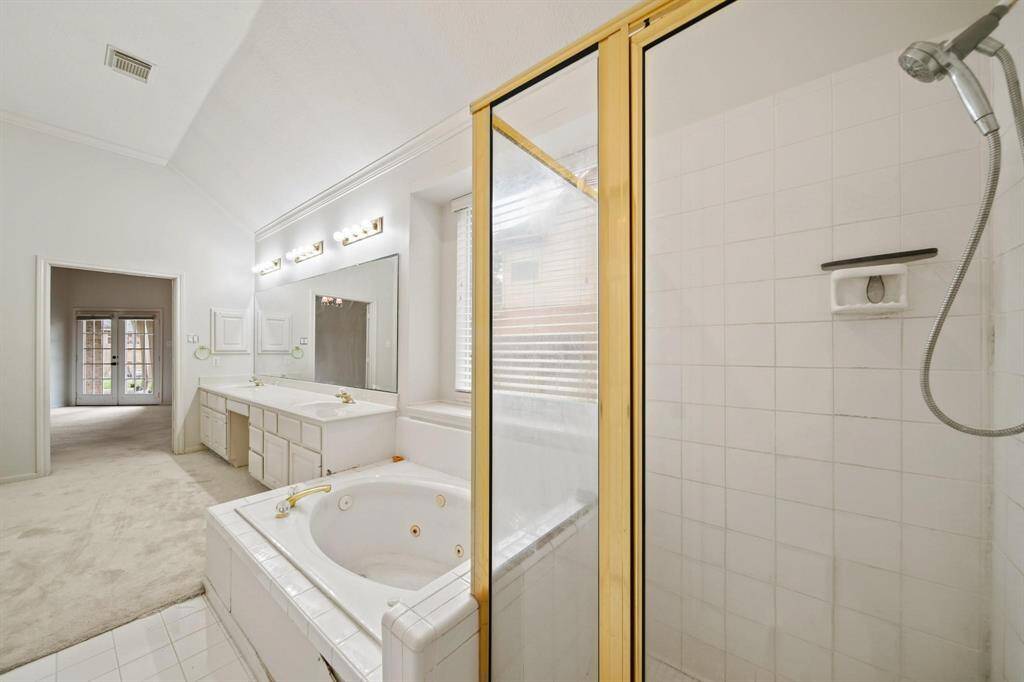 The bathroom boasts a large soaking tub, alongside a separate glass-enclosed shower, adding a touch of elegance.