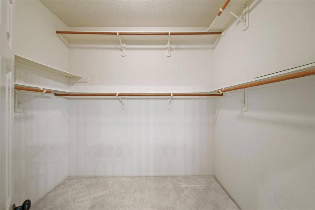 Spacious walk-in closet featuring multiple hanging rods, providing ample space for organizing clothing.