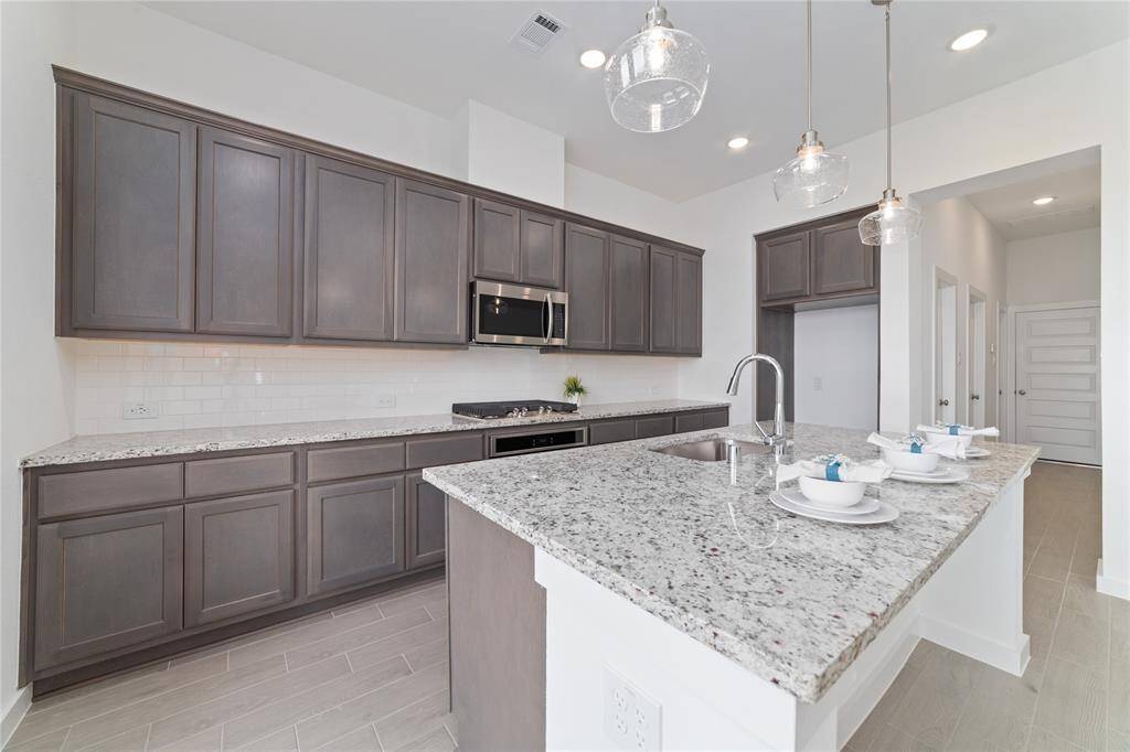 Side view of the kitchen with contemporary cabinetry, microwave, gas stove, and lots of counter space