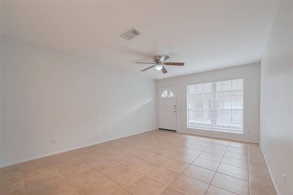 The living room has gorgeous tiles, a large picture window providing an abundance of natural light and neutral coloring.