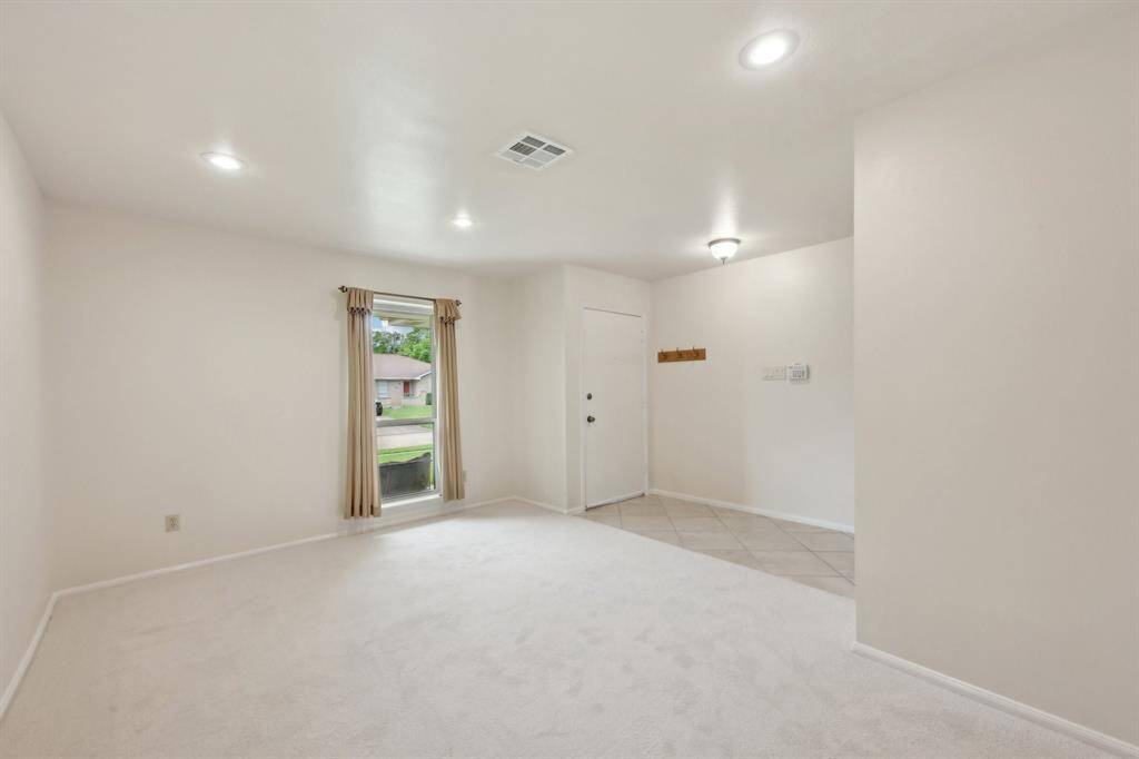 Formal living room off the entry hall is a large space that offers new owners flexibility. New carpet, paint, recessed lighting, and new windows add value and beauty.
