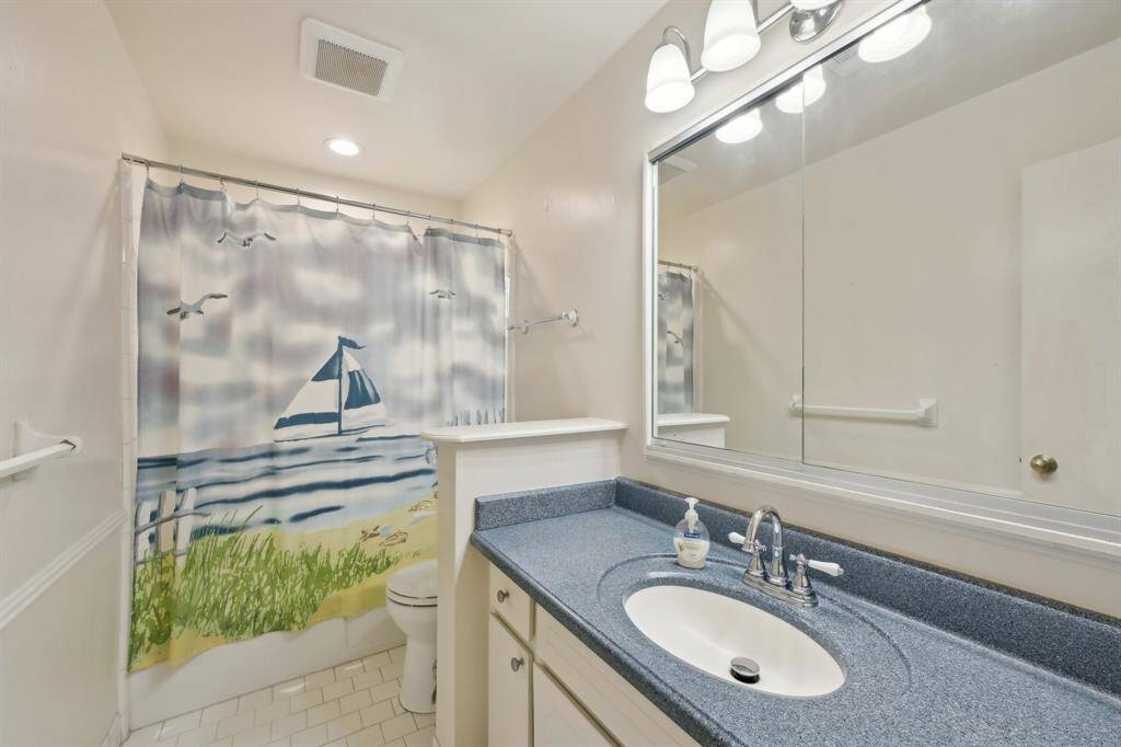 Secondary full bath has updated Corian countertops, framed mirror, and updated lighting. Under-counter storage is plentiful.