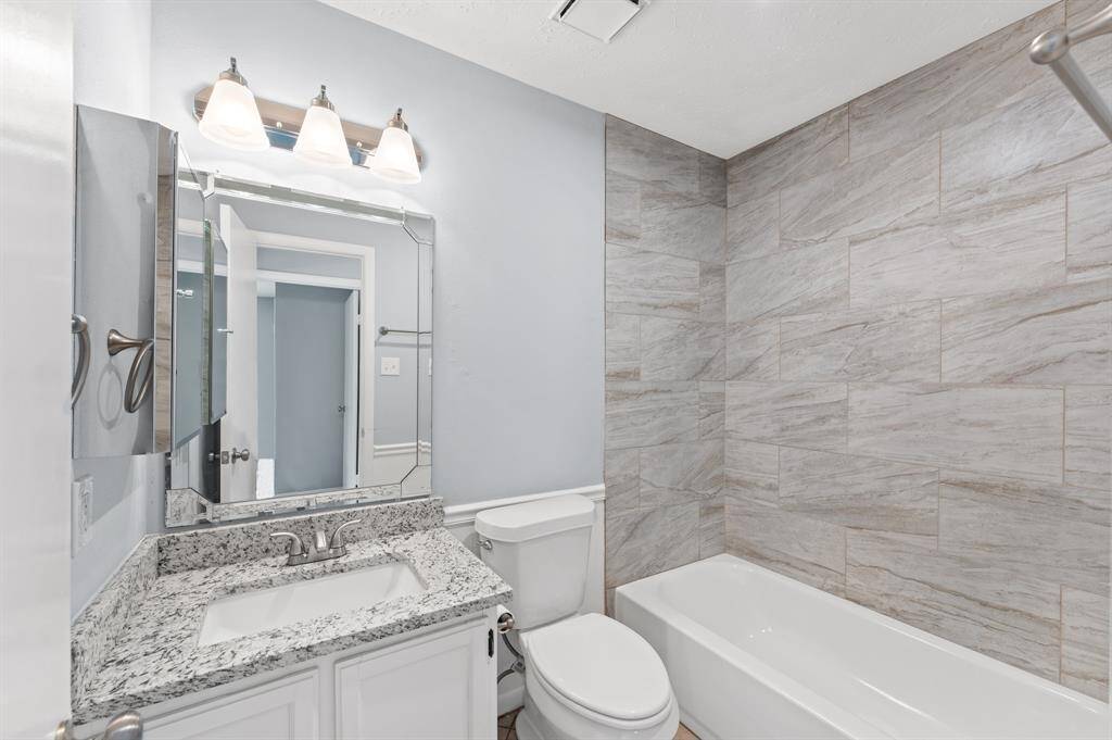 Elegantly updated bathroom with granite countertop and new tub accented with neutral tile.