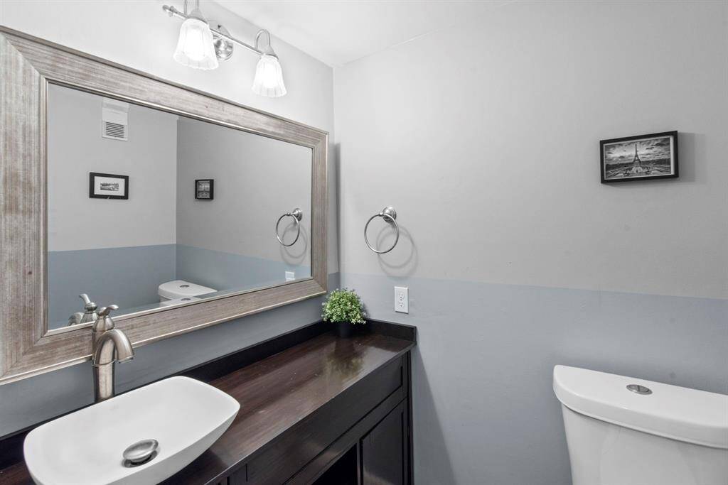 The downstairs half-bath is stylish and modern with a vessel sink, framed mirror, and a calming tone wall palette.