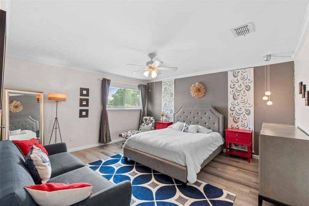 Spacious and stylish primary bedroom featuring a modern accent wall. Natural light streams in through a wide window, creating a bright and calming retreat.