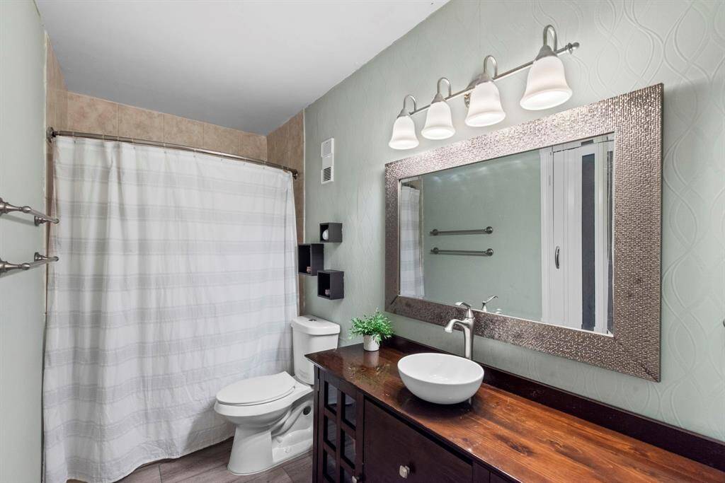Updated and stylish, the secondary bathroom includes a large framed mirror, vessel sink, and a soothing soft green palette with texture-rich walls.