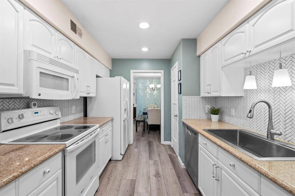 The cooking area is streamlined and classic with an electric range, built-in microwave, and polished countertops for easy prep.
