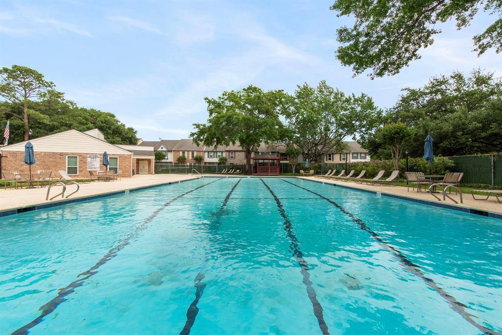 Enjoy sunny days at the large community pool, complete with lounge chairs, mature trees, and a clubhouse backdrop for added comfort.