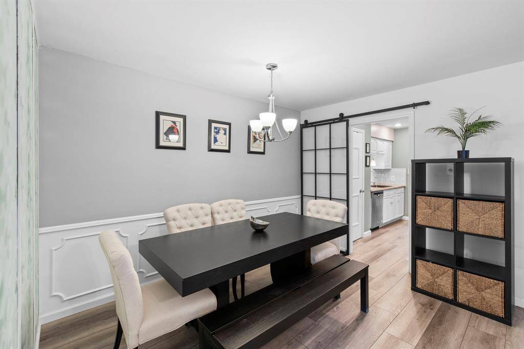 Chic and functional, the dining space features tufted seating, a modern light fixture, and direct access to the kitchen through a sliding door.