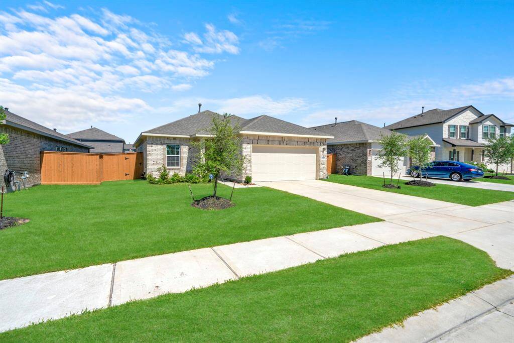 Charming single-story brick home with a two-car garage and well-maintained front lawn. The property features a wooden fence for privacy and is situated in a peaceful neighborhood with similar homes.