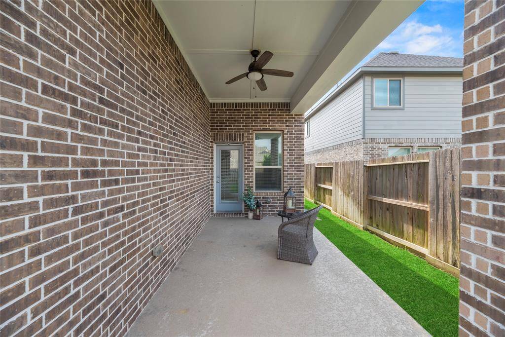 A covered patio with a ceiling fan, brick walls and features an area for seating and relaxation. This backyard is truly low maintenance which is great for everyone's busy schedules!