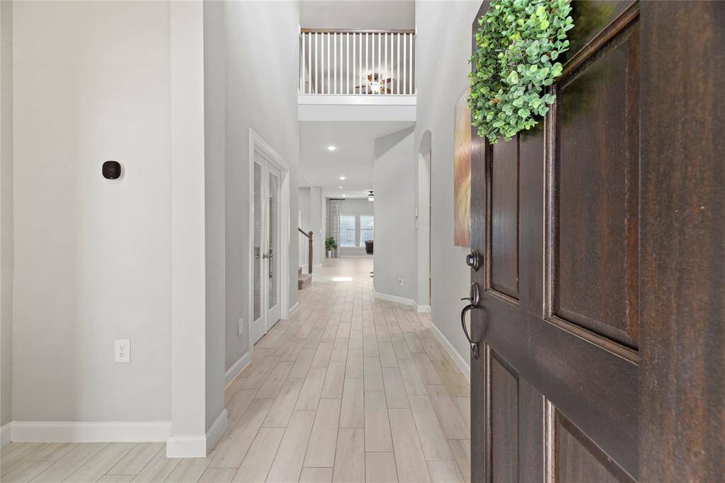 Welcome to a bright and inviting entryway featuring a high ceiling, light flooring, and a view into the spacious living area. The open layout offers a modern and welcoming atmosphere, perfect for family gatherings.
