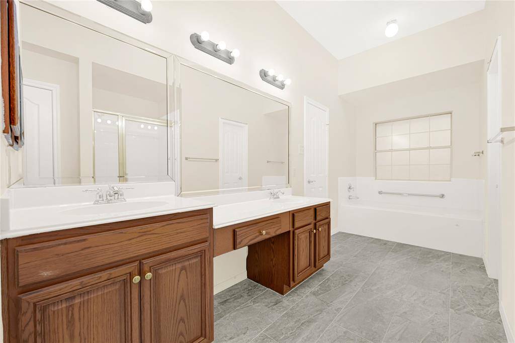 This primary bathroom features a jetted tub, perfect for relaxation. Completing the space is a vanity with dual sinks, offering ample counter space, and a separate shower for convenience.