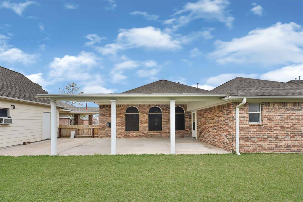 Spacious backyard patio with a covered patio. It features arched windows with solar screens. This space is perfect for outdoor activities and relaxation.