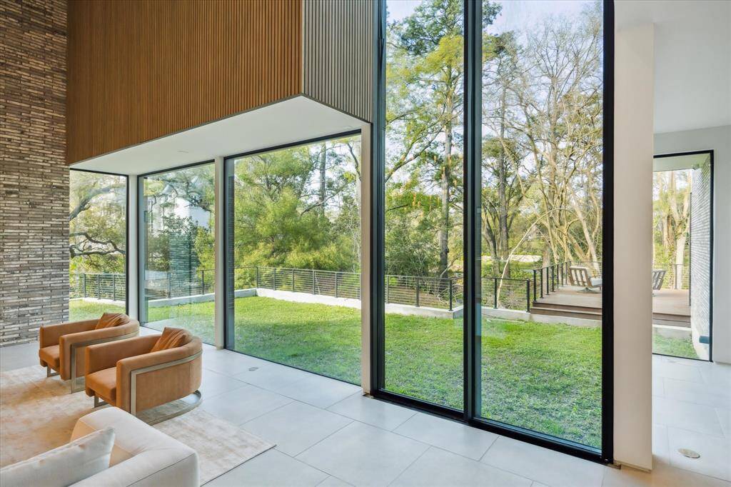 Panoramah windows offer sweeping views of the serene backyard, while a double-height automated door seamlessly transitions the indoors to the outdoors.
