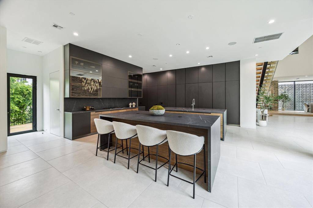 The kitchen boasts dual islands, providing ample workspace and a perfect setting for both culinary preparation and casual gatherings, enhanced by luxurious Poliform Alea cabinetry and top-of-the-line Gaggenau and Miele appliances.