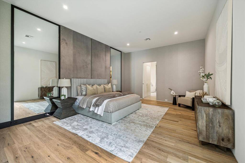 The first-floor primary retreat features elegant Maxwell White Oak hardwood flooring, custom mirrored walls, and a large window overlooking the lush back lawn, with direct access to a luxurious ensuite bathroom, spacious walk-in closet, and a private utility room for added convenience.