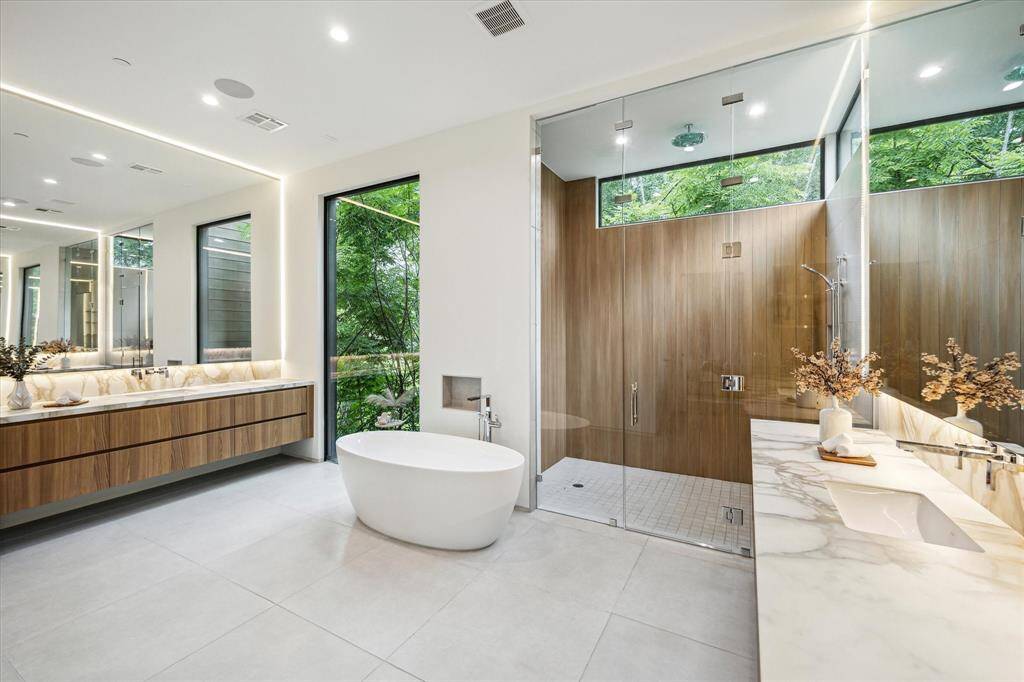 The primary bathroom is a spa-like sanctuary, featuring a Victoria + Albert freestanding tub with a Dornbracht wall-mounted faucet and tub filler, a Dornbracht Lulu shower set with a ceiling-mounted rain shower and MEM controls, and the luxury of dual primary water closets.