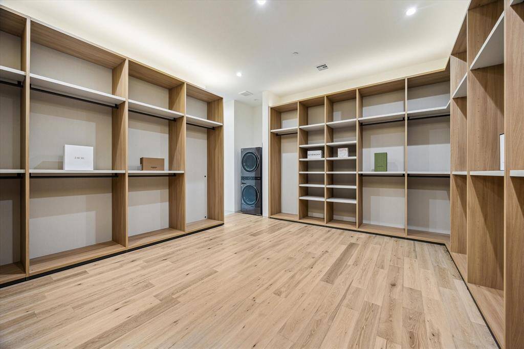 The boutique-style primary closet offers a thoughtfully designed layout with multiple levels of hanging rods, open shelving, and ample storage, creating a luxurious and organized dressing space. Custom finishes and built-in features elevate the experience, combining function with high-end design. For added convenience, the closet also includes a dedicated set of stackable washer and dryer, allowing for effortless first-floor laundry without the need to go upstairs.