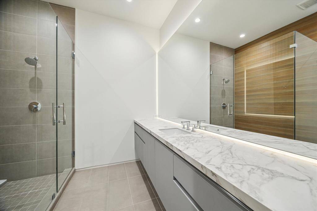 The accompanying ensuite bathroom features luxurious countertops of Moderno porcelain in Matte Arabescato, paired with a walk-in shower that adds both style and functionality to the space.