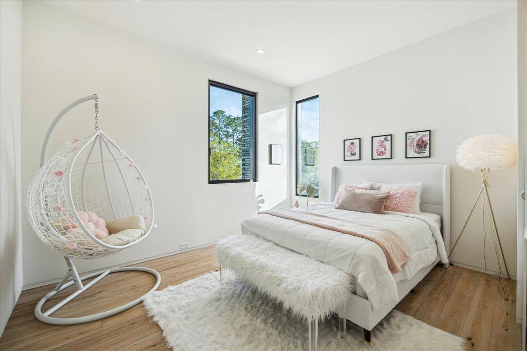 The guest bedroom is beautifully appointed with double corner windows that flood the space with natural light, recessed lighting, and engineered wood flooring. Neutral wall paint creates a calming atmosphere, while a custom closet system and an ensuite bath add both functionality and luxury to the room.
