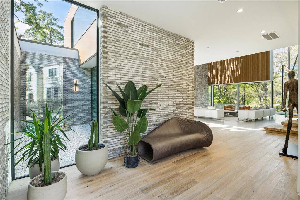 Step inside to a refined entryway featuring brick accents, soaring 10'10" ceilings, and views of the serene courtyard beyond. Recessed can lighting enhances the warm, inviting ambiance while highlighting the thoughtful architectural details. This elegant space sets the stage for the contemporary sophistication that unfolds throughout the home.