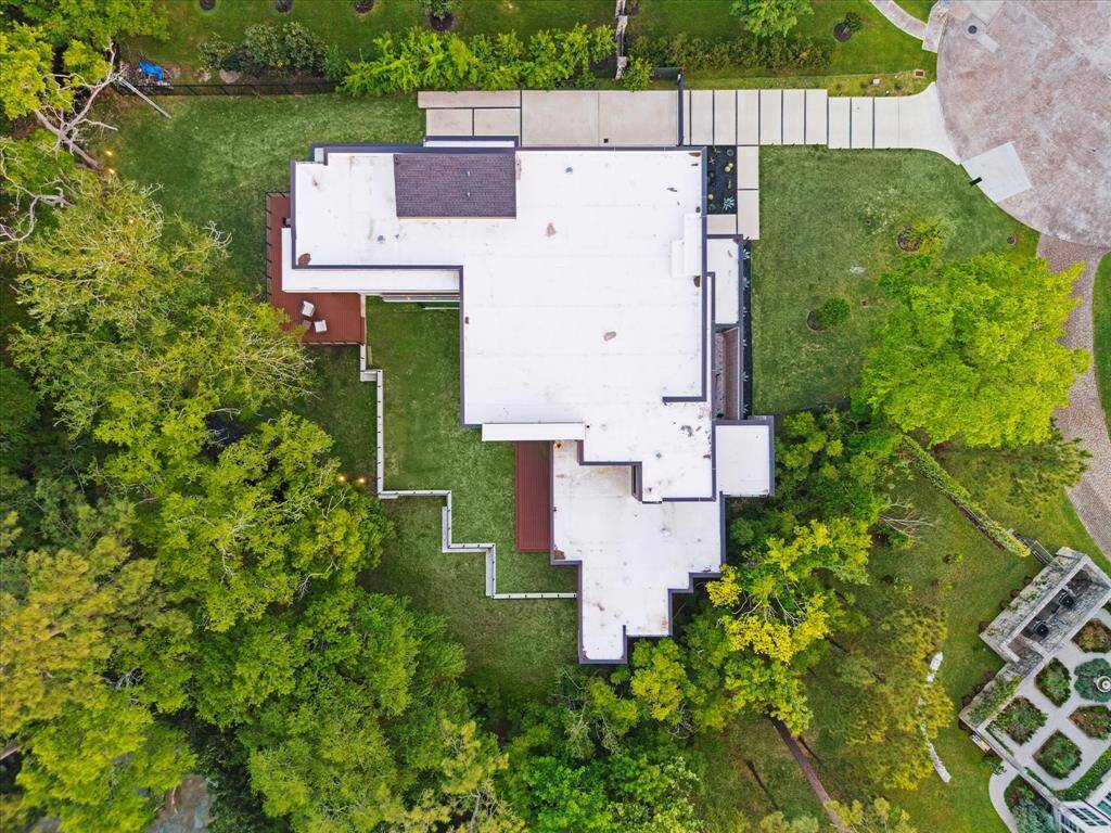 An aerial view reveals the home’s breathtaking setting—an expansive, serene, wooded lot that offers unmatched privacy and natural beauty. Towering trees and lush greenery surround the property, creating a peaceful retreat just minutes from the city. This extraordinary lot is a rare find in coveted Piney Point Village.