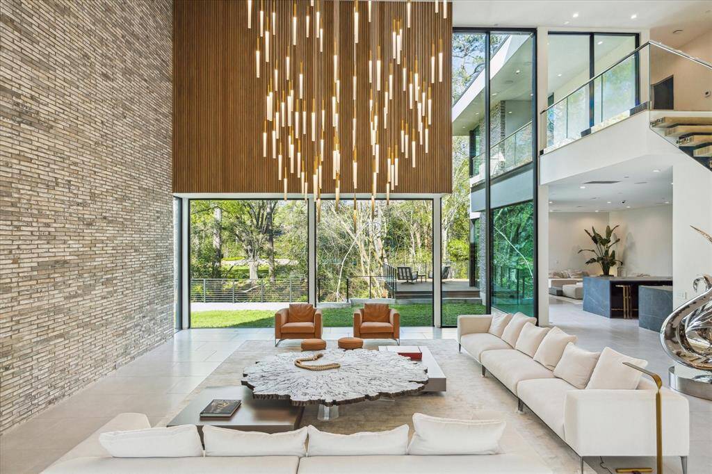 The double-height living room serves as the stunning focal point of the home, anchored by Maxwell White Oak hardwood floors and a sleek 68” Eco-Smart clean-burning linear fireplace. Above, 18 Bomma Large Soap Pendants in silver, blue, and gold create a captivating art installation of light. A striking Innowood architectural feature in Tasmanian Oak adds warmth and texture, elevating the space with modern elegance.