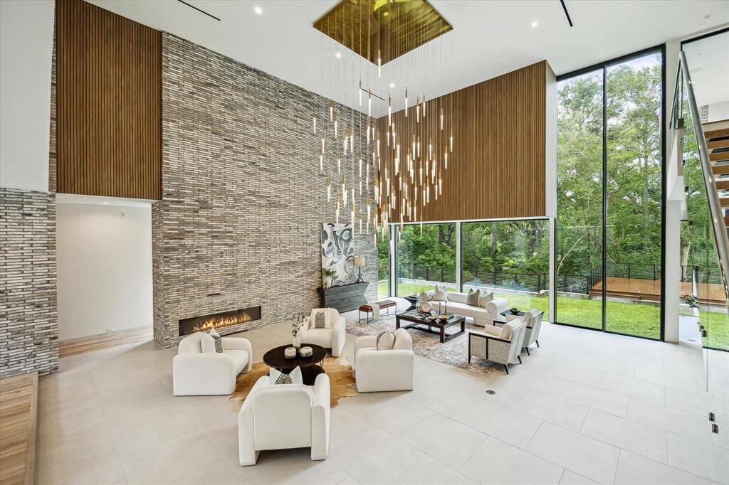 The living room's sleek linear fireplace creates a cozy yet modern focal point, perfectly complemented by the dramatic 18-piece Bomma Large Soap Pendant installation in shimmering silver, blue, and gold. An Innowood architectural feature in Tasmanian Oak adds natural warmth and refined texture. Together, these elements create a space that is both striking and sophisticated.