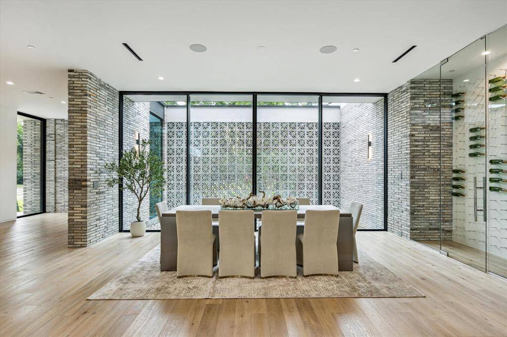 The formal dining room overlooks a tranquil courtyard, creating a serene backdrop for intimate dinners or festive gatherings. Warm Maxwell White Oak hardwood flooring grounds the space, while a custom wine cabinet adds both function and flair.