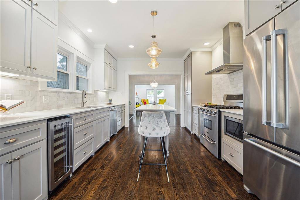 Updated kitchen with stainless appliances, quartz counters, white honed Carrera marble backsplash and Kichler lighting.