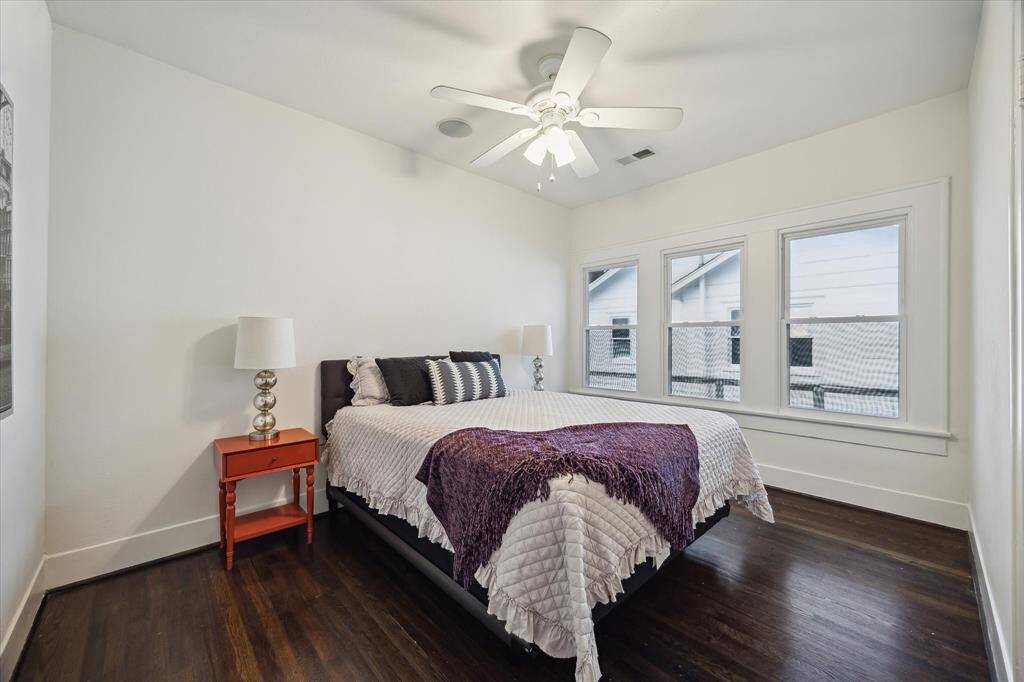 Spacious and bright, the primary bedroom features clean lines, hardwood floors, and a trio of windows for natural light.