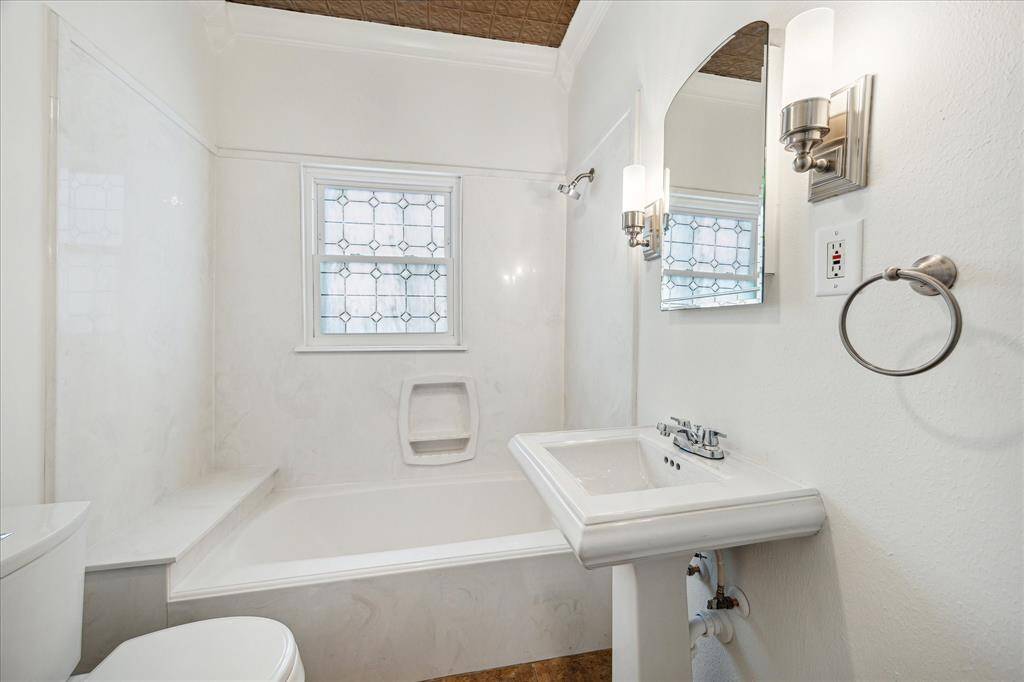Primary bathroom with tile floors, sconce lighting, pedestal sink and a tub/shower combo.