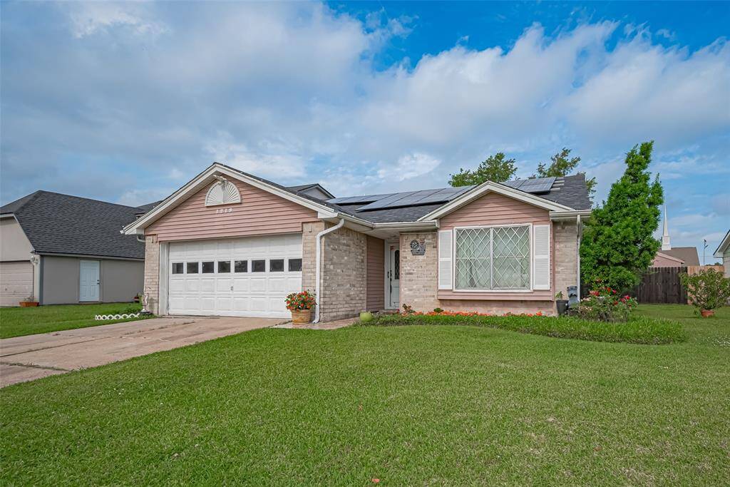 Charming single-story home with a two-car garage, featuring a well-maintained lawn and solar panels on the roof. The exterior has a mix of brick and siding, with a large front window and mature landscaping.