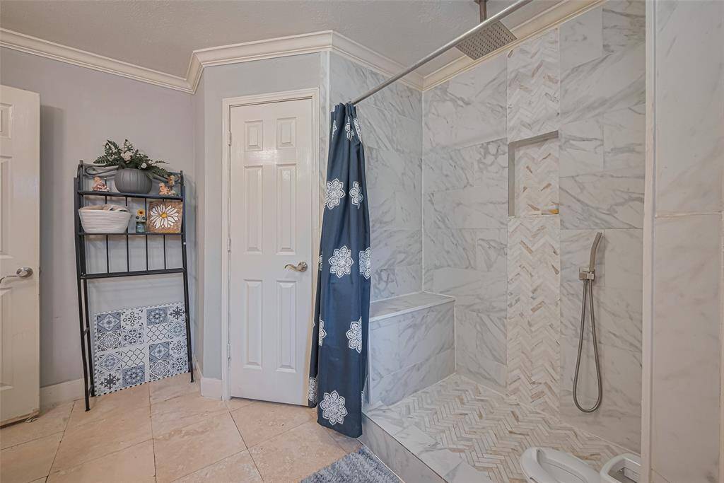 Spacious, modern shower with marble-style tiles and a rainfall showerhead